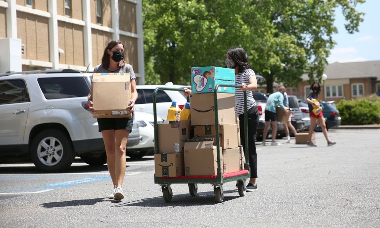 Two females walking through Dawson Hall parking lot with cart